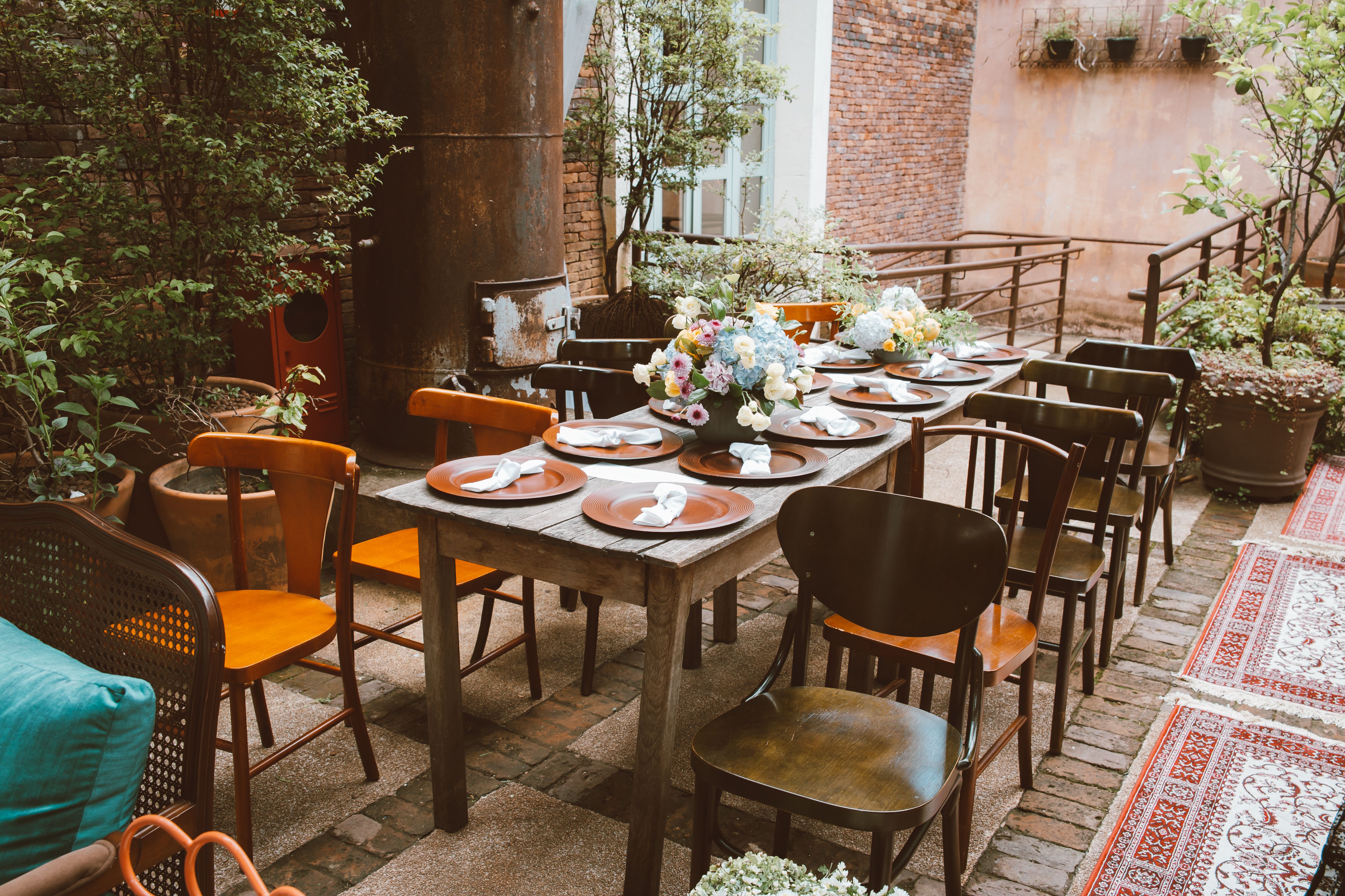 Rustic outdoor dining table set with flowers and wooden chairs for entertaining guests