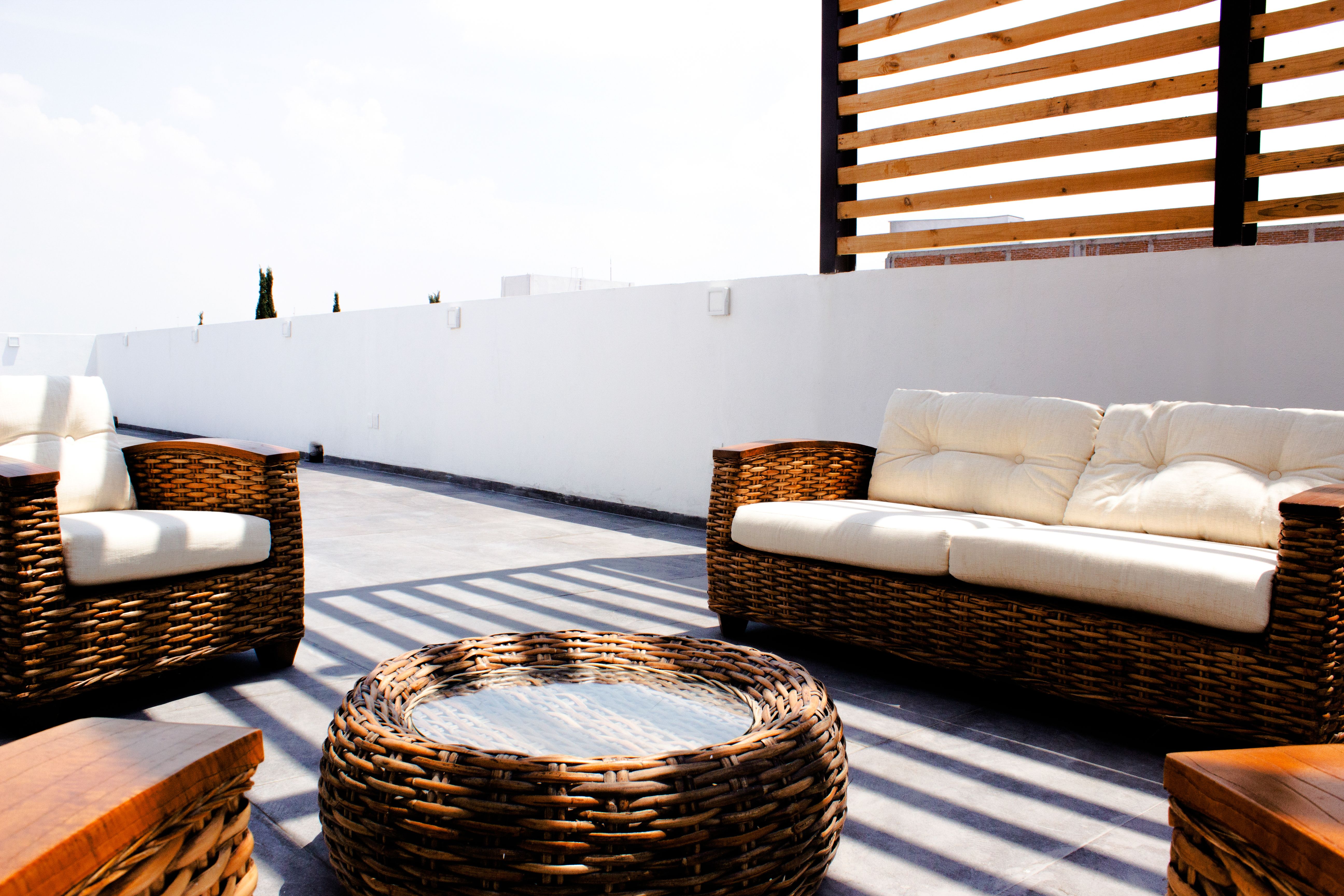Sunny rooftop terrace with stylish wicker furniture and neutral cushions